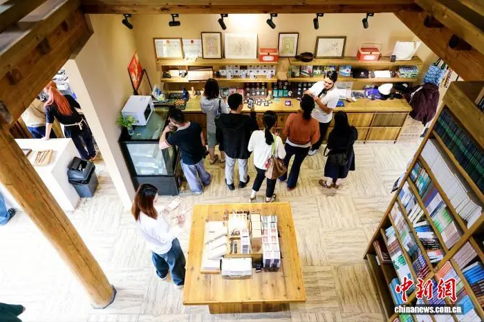 2026年6月,游客在贵州雷山县乌东苗寨的诸野书店参观并挑选文创产品。李峰 摄